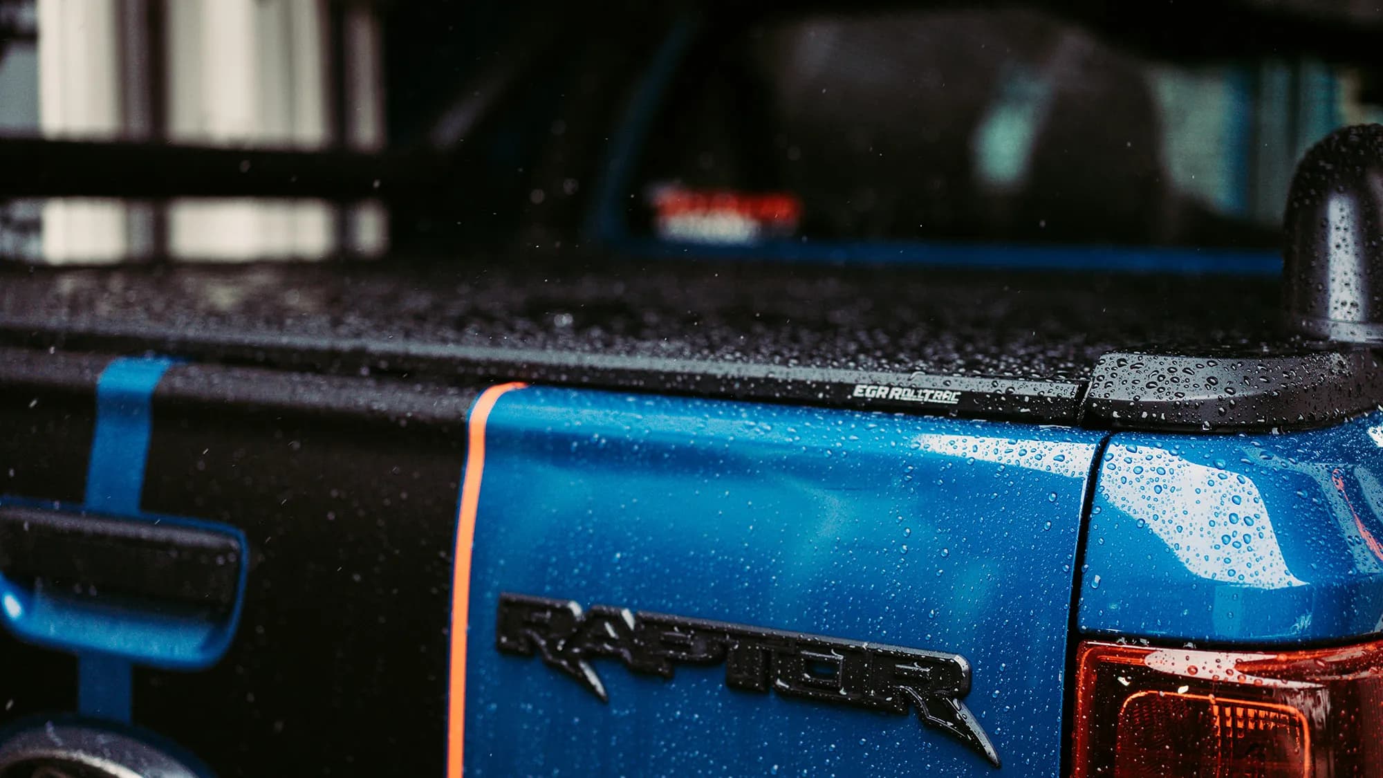 Close-up of an EGR RollTrac roller cover on a blue ute tray with rain droplets